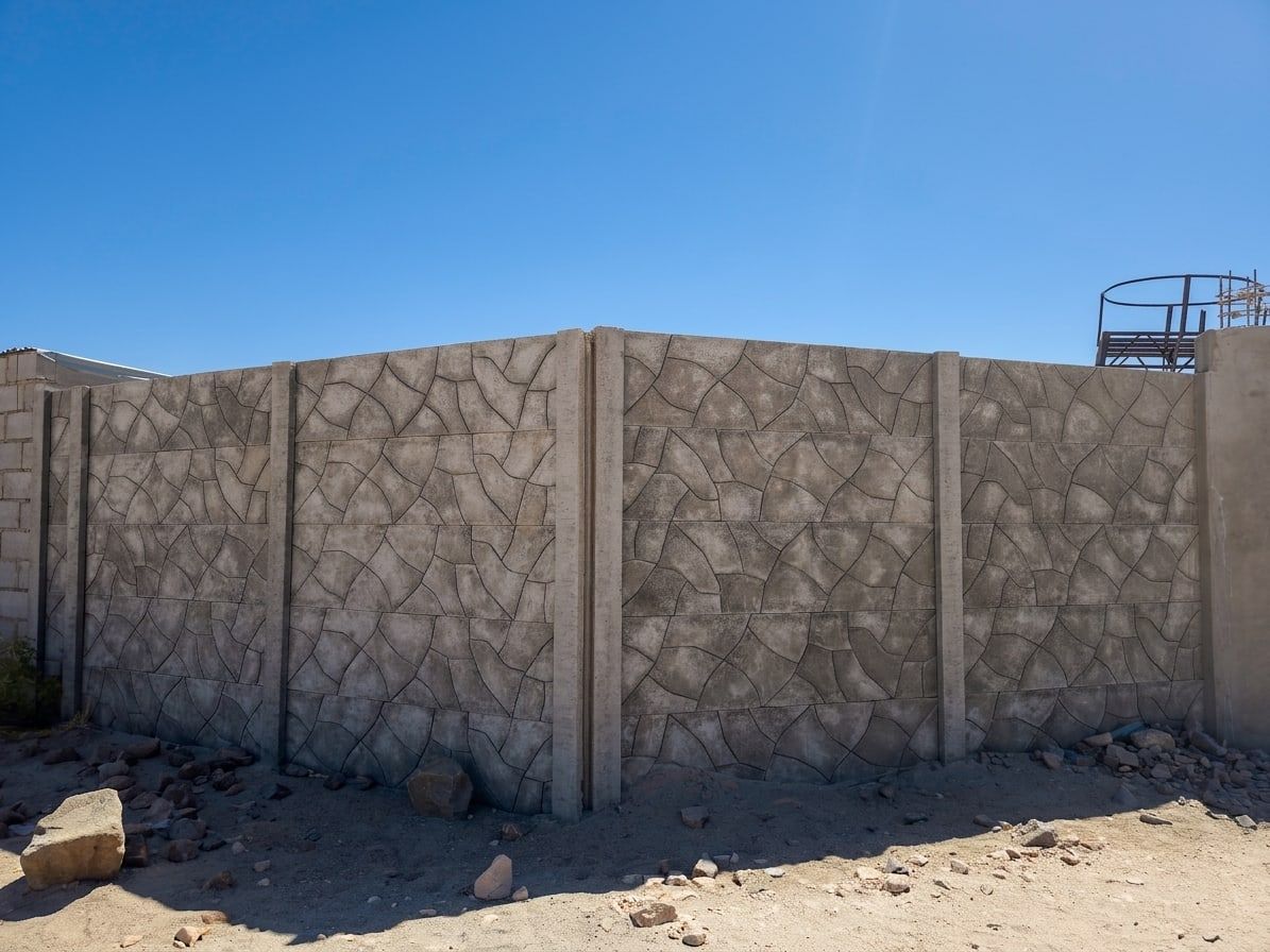 Esquina de un cerco premium con diseño piedra laja, terminado sobre terreno de desierto